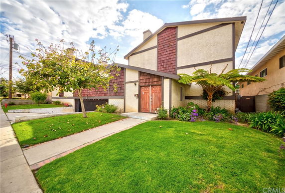 Front view of a two-story house with a distinct architectural design and lush front lawn.