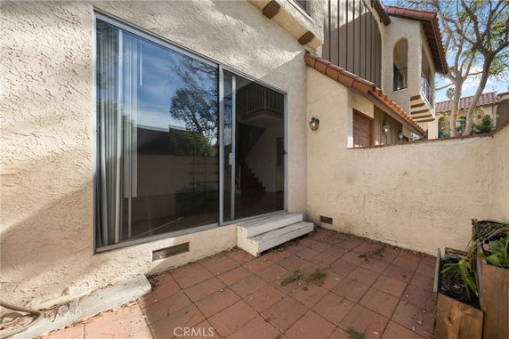 View of a house with glass sliding doors leading to a small patio area.
