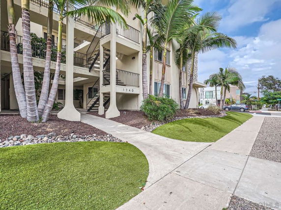 Front view of a multi-story building with exterior staircases and palm trees.