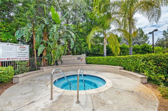 Outdoor swimming pool area with tropical plants and a spa section.