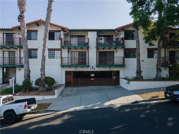 Front view of a three-story building with multiple balconies and a central garage entrance.