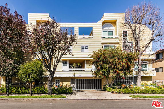 Front view of a multi-story residential building with a yellow facade and balconies.