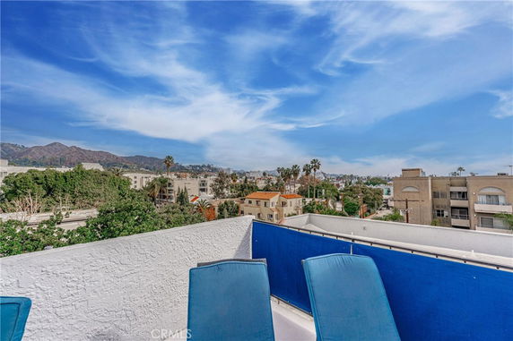 Panoramic view from a rooftop overlooking a cityscape with mountains in the distance.