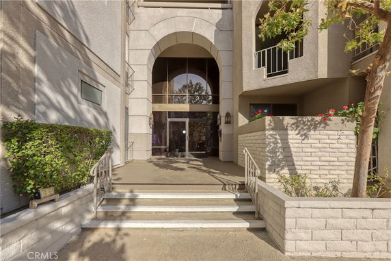 Front view of a multi-story building entrance with steps and large arched doorway.
