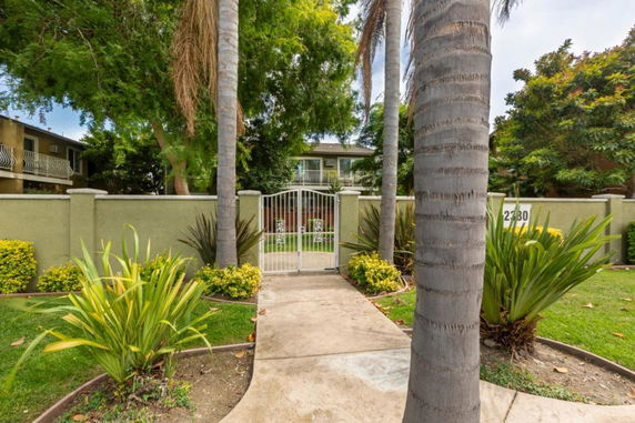 Front view of a two-story building with a gated entrance and surrounding greenery.