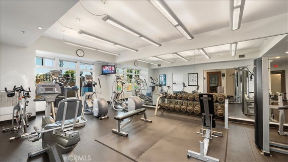 Indoor gym with various exercise equipment and mirrors on the walls.