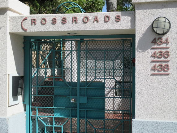 Entrance of a building named 'Crossroads' with iron gate and building numbers.