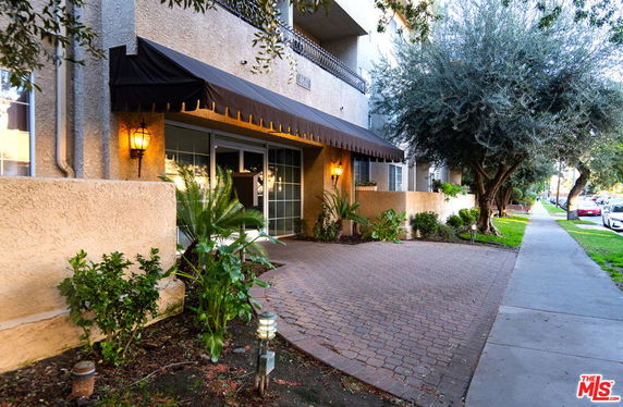 Front view of a multi-story building with an awning and pathway.