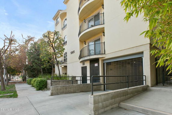 Front view of a multi-story building with balconies and a gated entrance.