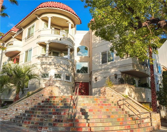 Front view of a multi-story building with balconies and a red tiled roof.