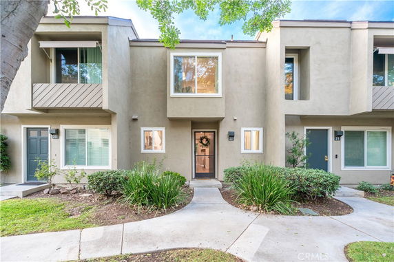 Front view of a modern two-story townhouse with large windows and a central entrance.