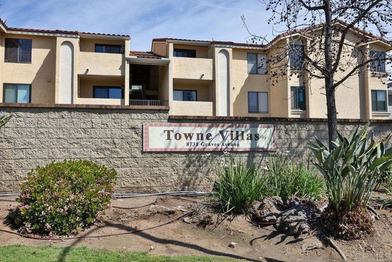 Front view of an apartment complex with multiple stories and a sign reading 'Towne Villas.'
