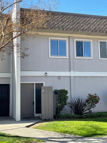 Front view of a two-story townhouse with a grey exterior and multiple windows.
