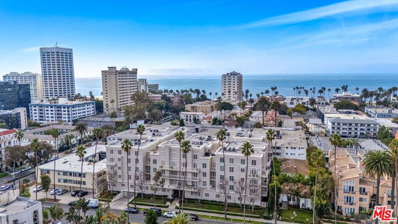 Aerial view of a coastal cityscape with multiple residential and commercial buildings near the shoreline.