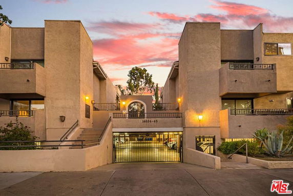 Front view of a multi-story building with gated parking entrance.