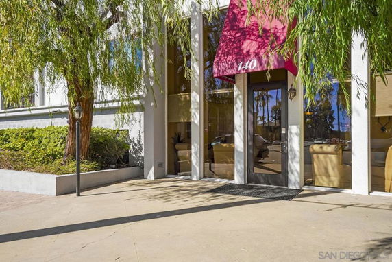 Front view of a building entrance with a red awning and glass door.