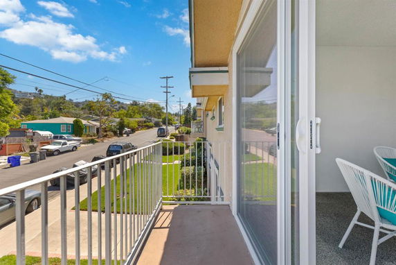 View from a balcony overlooking a suburban street with houses and parked cars.