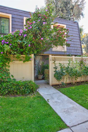 Front view of a two-story building with wooden fencing and flowering plants.