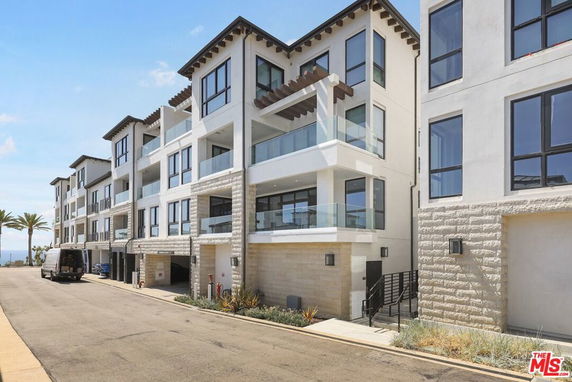 Front view of a modern multi-story residential building with glass balconies.