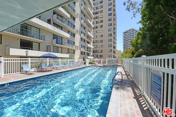 View of a swimming pool beside a tall residential building.