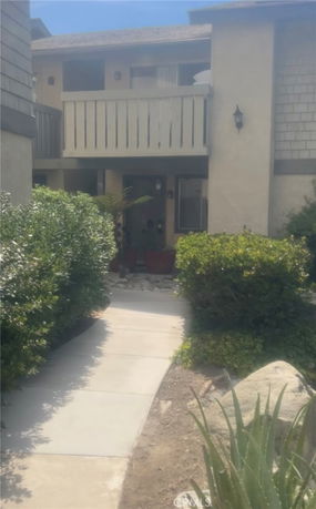 Front view of a multi-story house with a balcony and walkway.