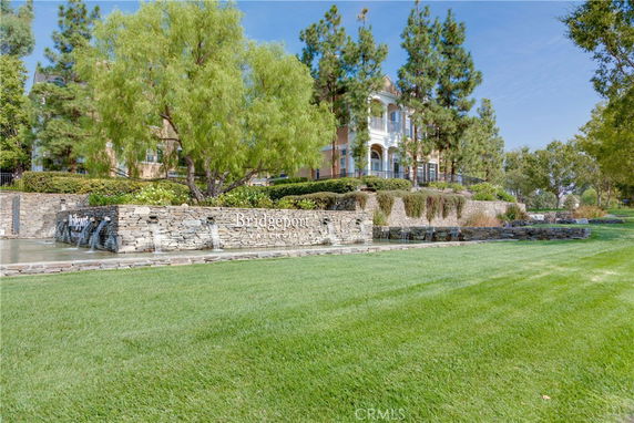 Front view of a building with trees and a stone wall with water features.