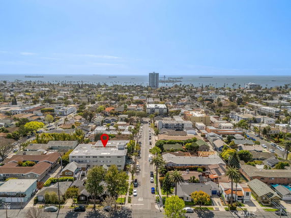 Aerial panoramic view of a residential area with cityscape and ocean in the background.