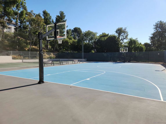 Outdoor basketball court with hoops and surrounded by trees.