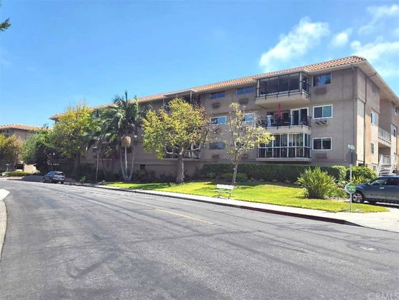 Front view of a multi-story building with balconies and a tiled roof.
