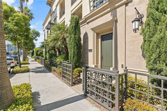 Front view of a multi-story building with decorative fencing and greenery.