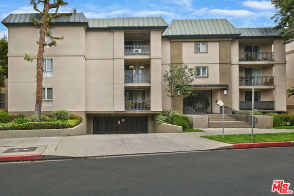 Front view of a multi-story residential building with balconies and a garage entrance.