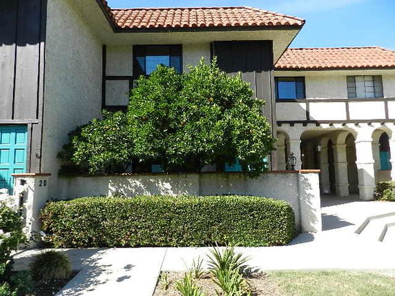 Front view of a two-story house with a red tile roof and arched entrance.