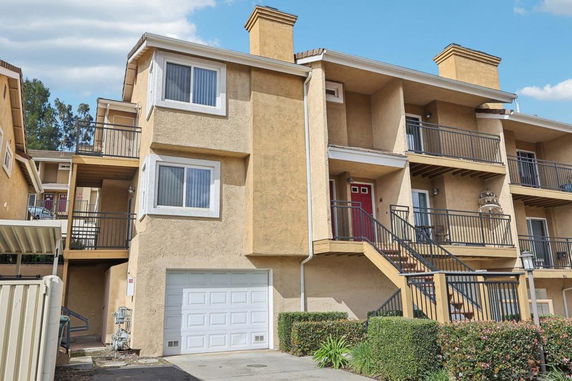 Front view of a multi-story apartment building with balconies and a garage.
