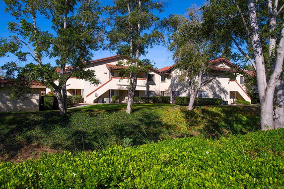 Front view of a two-story house with beige walls and red-tiled roofs.