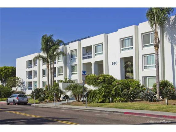Front view of a three-story apartment building with balconies and large windows.