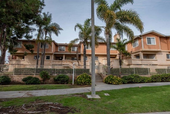 Front view of a multi-story residential building with palm trees.