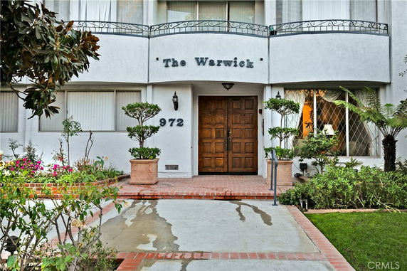Front view of a building entrance with garden and pathway.