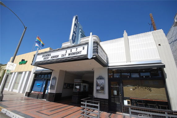 Front view of a theater with a marquee displaying movie titles.