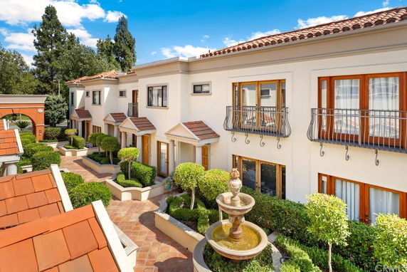 Front view of a row of two-story townhouses with balconies and tiled roofs.