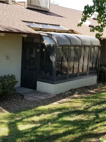 Front view of a house with a sunroom and shingled roof.