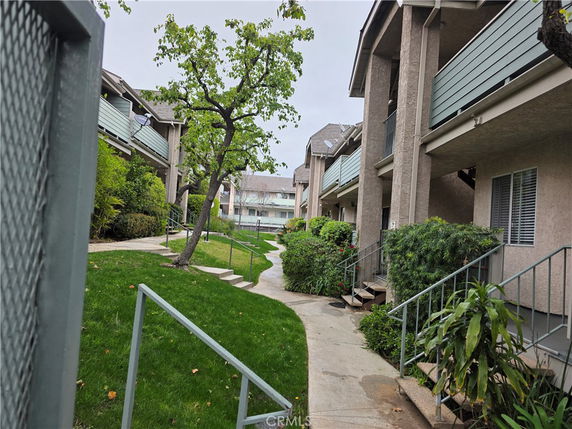 Front view of a residential apartment complex with balconies and greenery.