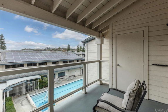 View from a balcony showing a building with solar panels and a swimming pool below.