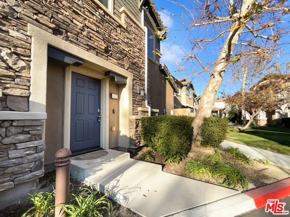Front view of a multi-story house with textured stone facade and a blue door.