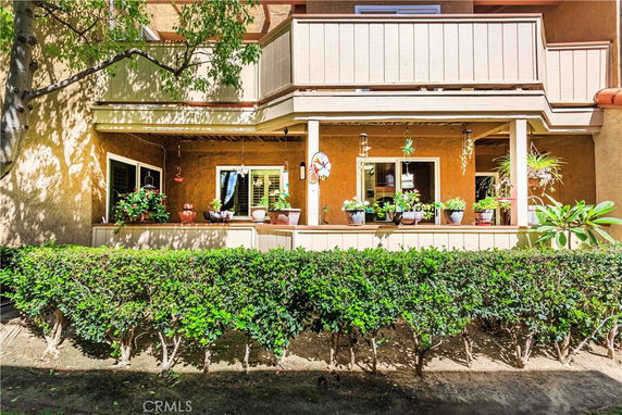 Front view of a multi-story house with a balcony and potted plants.