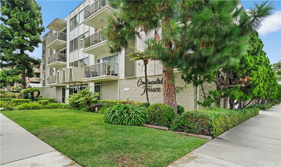 Front view of a multi-story building with balconies and landscaping.