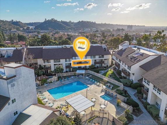 Aerial view of apartment complex with a central swimming pool and surrounding buildings.
