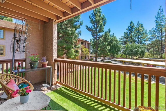 View from a balcony overlooking a landscaped area with trees and neighboring buildings.