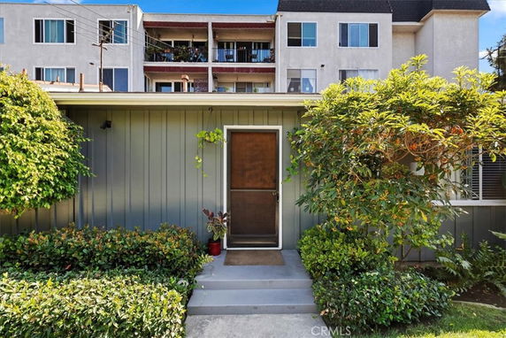 Front view of a residential building with a single entry door and surrounding greenery.