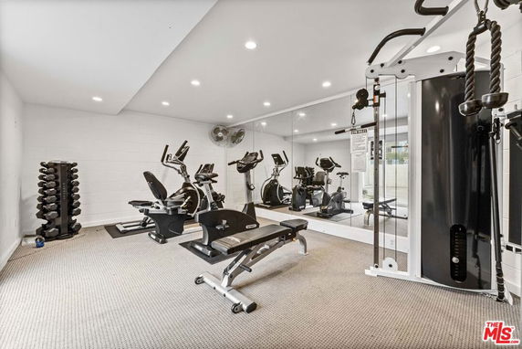 Indoor gym area with exercise equipment and mirrors on the walls.