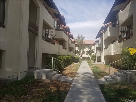 Walkway between two rows of multi-story buildings with balconies.